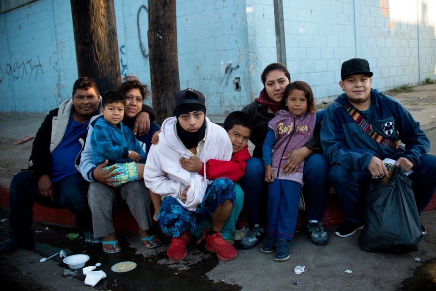 A family from Honduras poses for a picture outside a temporary shelter in Tijuana, Baja California State, Mexico, near the U.S.-Mexico border on November 26, 2018.