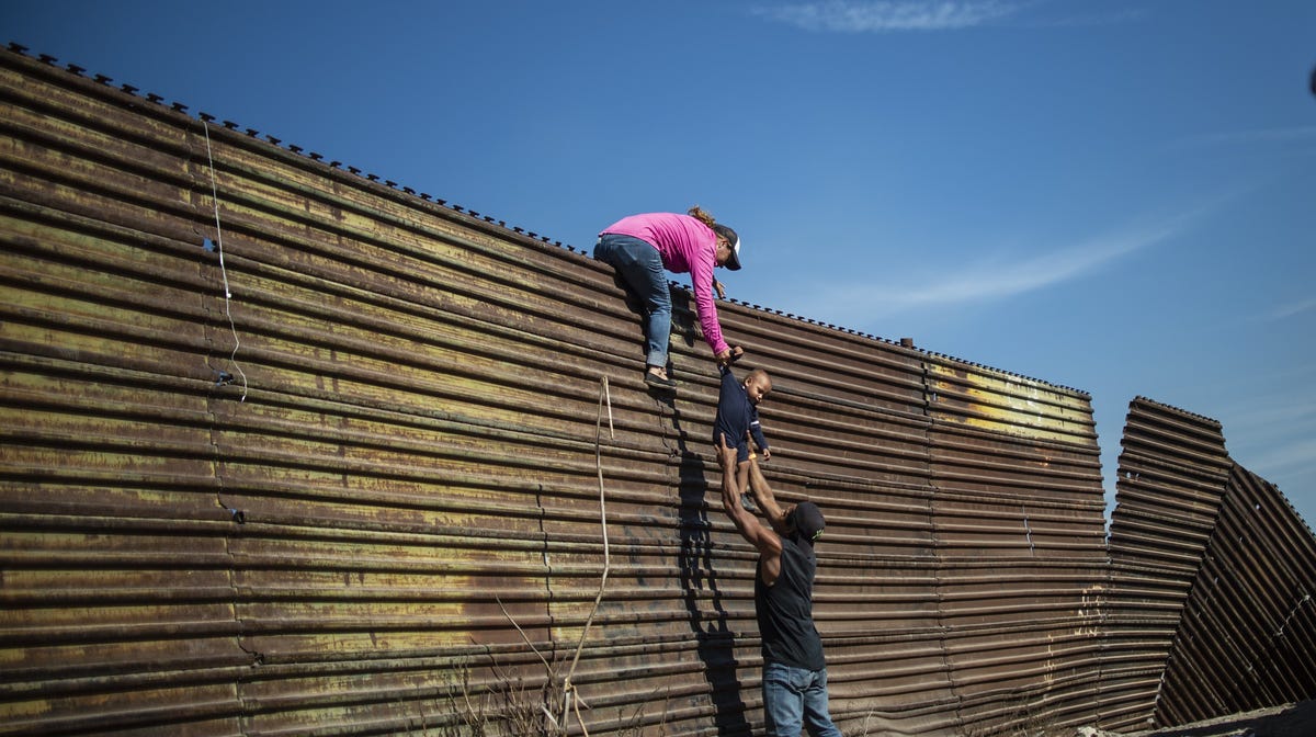 Central American migrants climb the border fence between Mexico and the United States, near El Chaparral border crossing, in Tijuana, Baja California State, Mexico, on November 25, 2018.