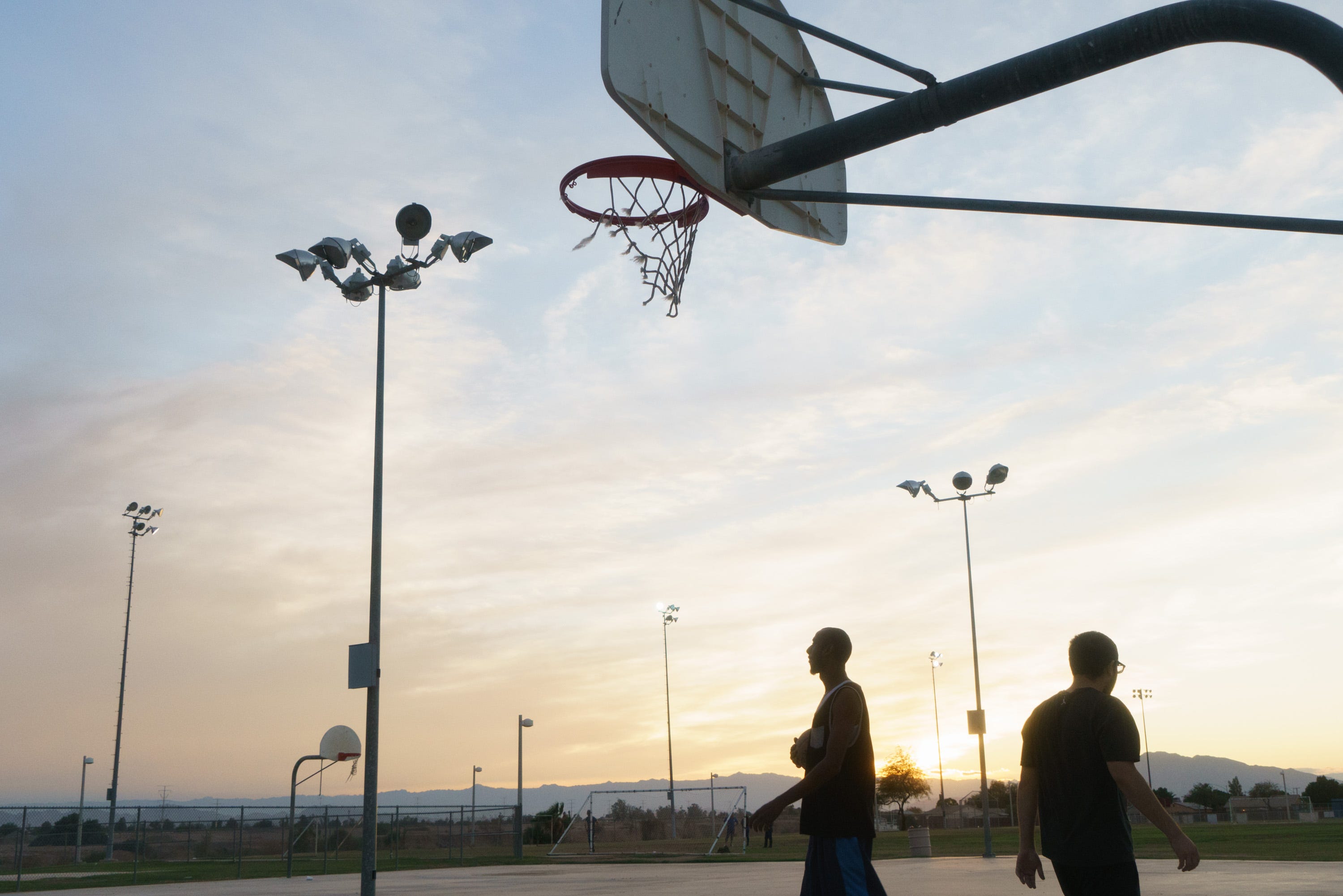 André Walker and Noor Hijazi play basketball at a park next to the New River in Calexico.