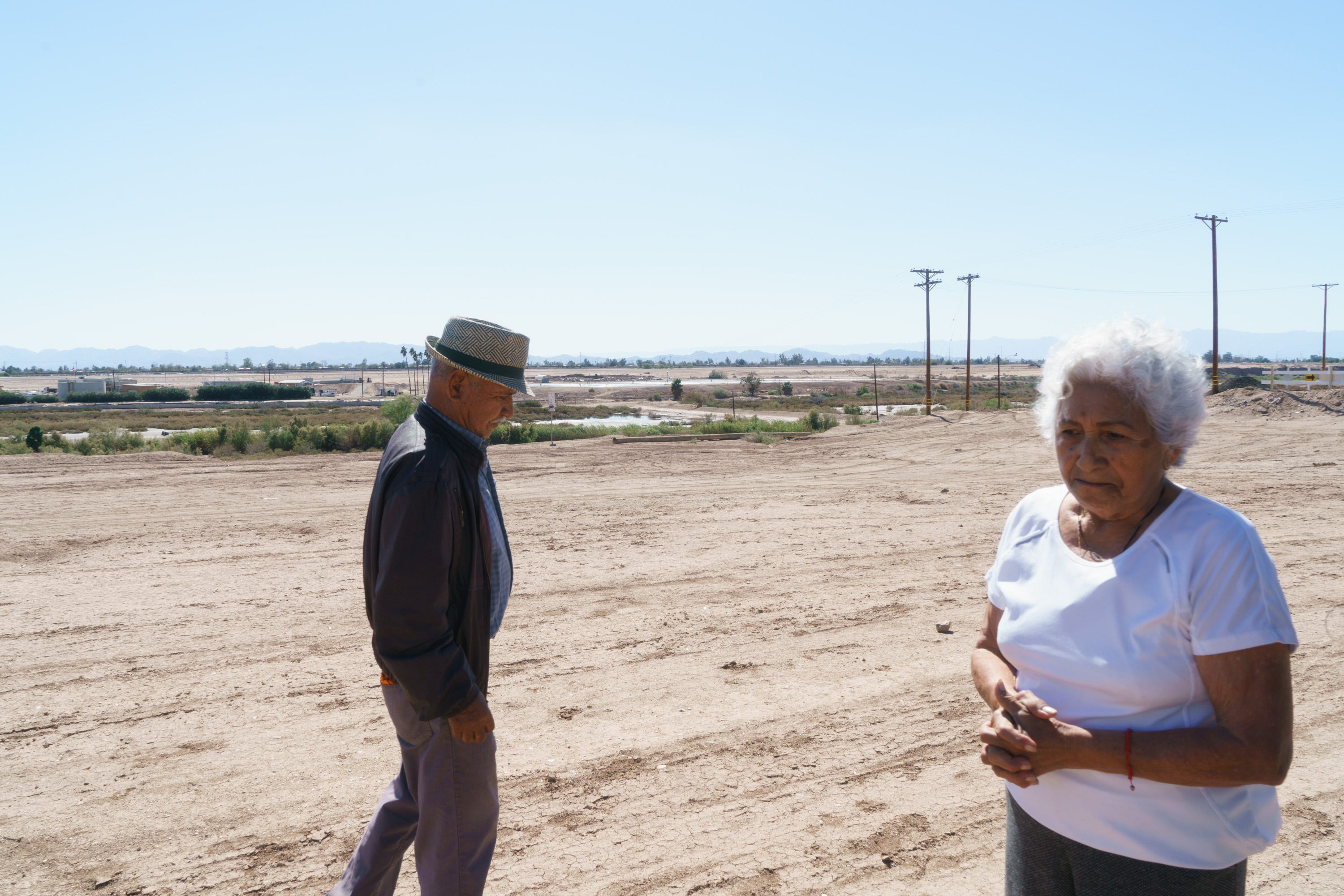 Miguel and Rebeca Zapata walk on a bare patch of dirt between their backyard and the banks of the New River.