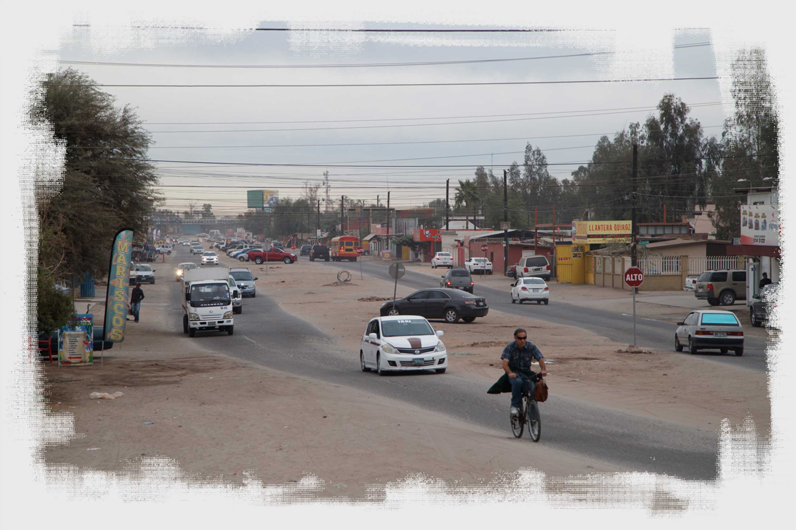 A man rides a bicycle on a busy street in the neighborhood Colonia Vicente Guerrero in Mexicali.