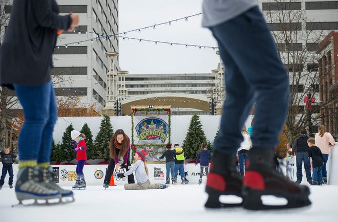 Gina Brace, center, laughs as she helps her daughter Gigi Brace, 9, after she fell during opening weekend for the Market Square ice skating rink Nov. 28, 2015.