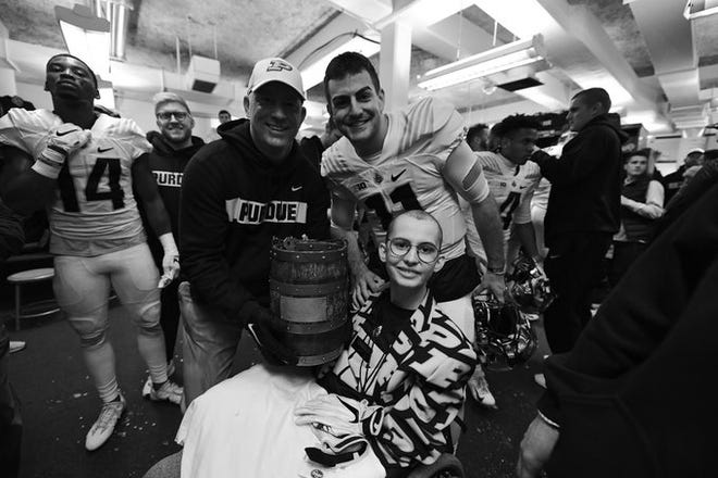 Tyler Trent sits next to Purdue football coach Jeff Brohm and quarterback David Blough after Purdue beat Indiana to win the Old Oaken Bucket on Nov. 24, 2018.