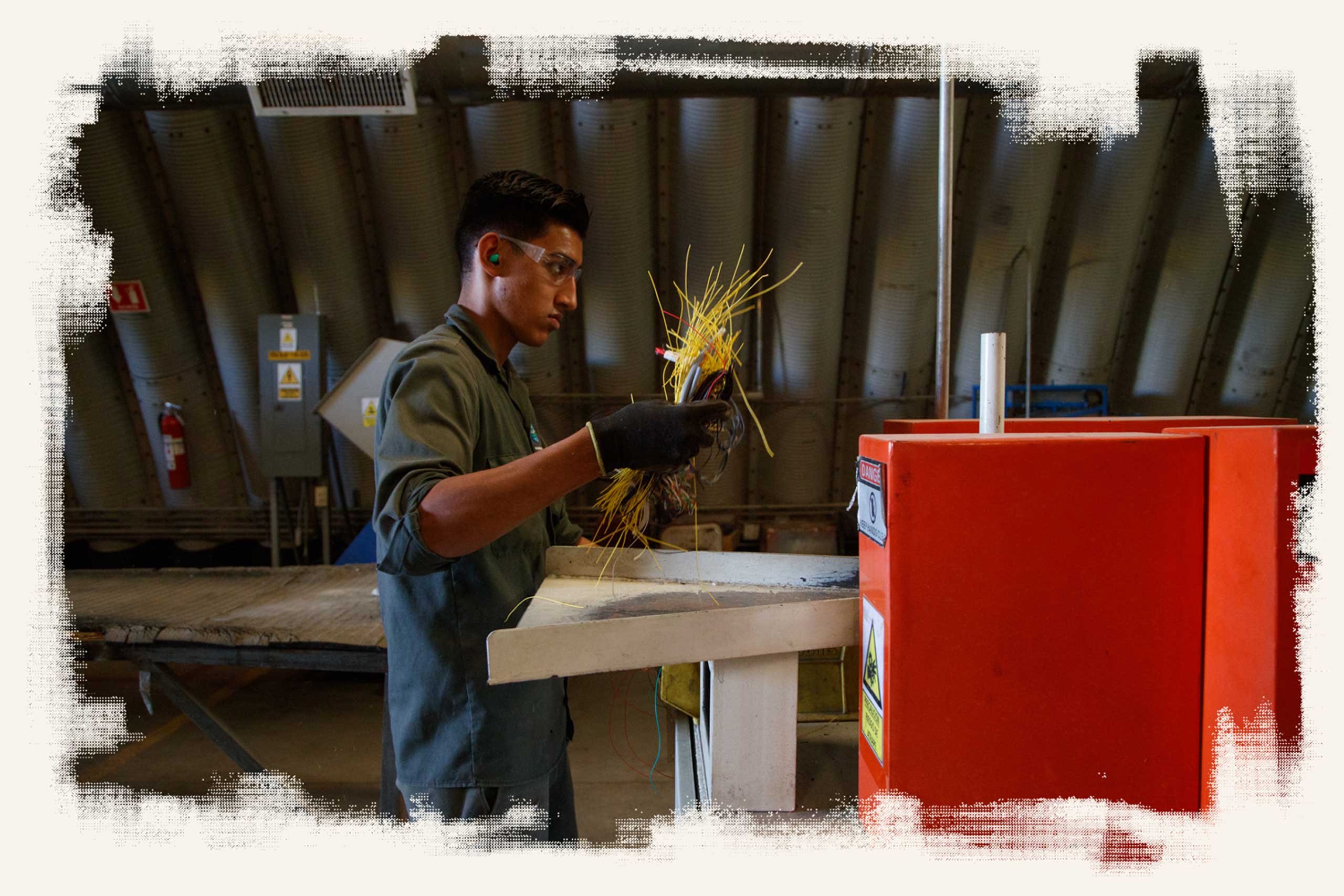 A worker at Green America Recycling & Recovery takes a handful of wires to a grinding machine to demonstrate how the wires are chopped up and recycled.