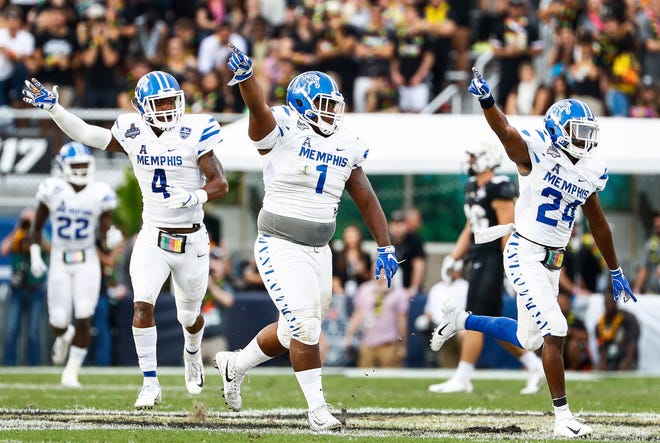 Memphis defenders (left to right) Josh Perry, O'Bryan Goodson and Tito Windham celebrate a fumble recovery against UCF during action at the AAC Championship Football game Saturday, December 1, 2018 in Orlando.