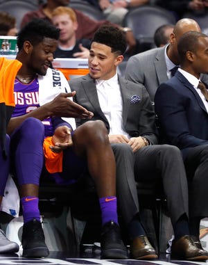 Suns' Deandre Ayton and Devin Booker talk about his suit on the bench during the first half at Talking Stick Resort Arena in Phoenix, Ariz. on November 30, 2018. 