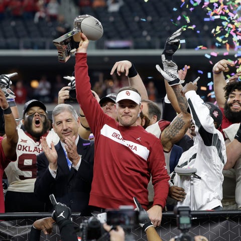 Oklahoma coach Lincoln Riley holds up the...