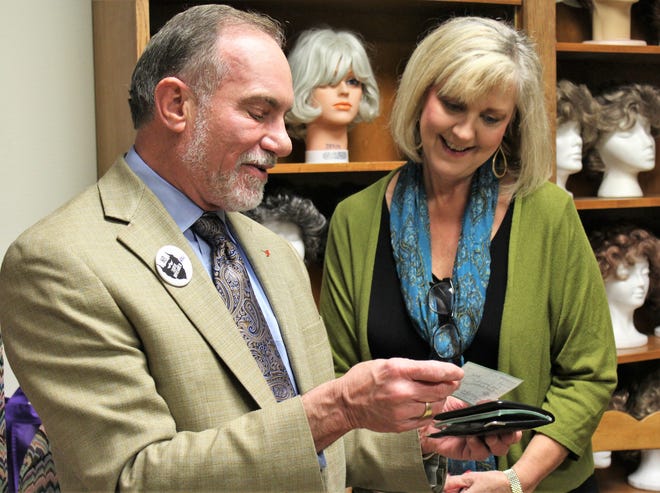 Scott Dueser, chairman, president and CEO of First Financial Bankshares, tears a personal check from his checkbook to present to Nancy Tyler, executive director of Cancer Services Network, on Monday. Dueser raised more than $10,000 for the United Way of Abilene's No Shave November, then matched donations. His check was for $10,243. He said he'll keep his month-old beard until April.