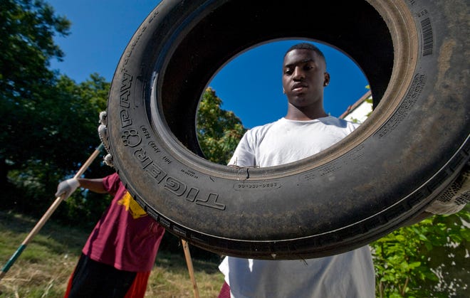 Calvin Alford, 17, a student at Melrose high school carries old tires from around an abandoned building off Park Ave. Over 40 volunteers, children, teens and adults from local schools and church groups spent their Saturday morning where they combined their efforts to clean up their neighborhood near the Melrose football stadium and the Orange Mound Community Center.
