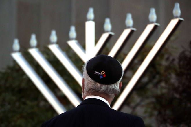 Rabbi Jeffrey Myers watches the installation of a menorah outside the Tree of Life Synagogue before holding a celebration on the first night of Hanukkah, Sunday, Dec. 2, 2018, in the Squirrel Hill neighborhood of Pittsburgh. A gunman shot and killed 11 people while they worshipped Saturday, Oct. 27, at the temple. (AP Photo/Gene J. Puskar)