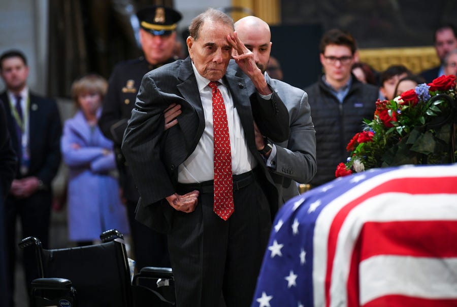 Former Sen. Bob Dole stands and salutes the casket of President George H.W. Bush who lies in state at the U.S. Capitol Rotunda.