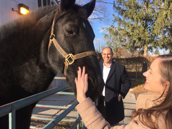 Melanie Markowicz, deputy executive of the Wayne County office of community and economic development, pets a Wayne County Sheriff's horse at Newburgh Mill, one of several old industrial mills that Wayne County hopes to convert to new destinations along Hines Drive and the Middle Rouge River. Khalil Rahal, county director of economic development, is in the background.