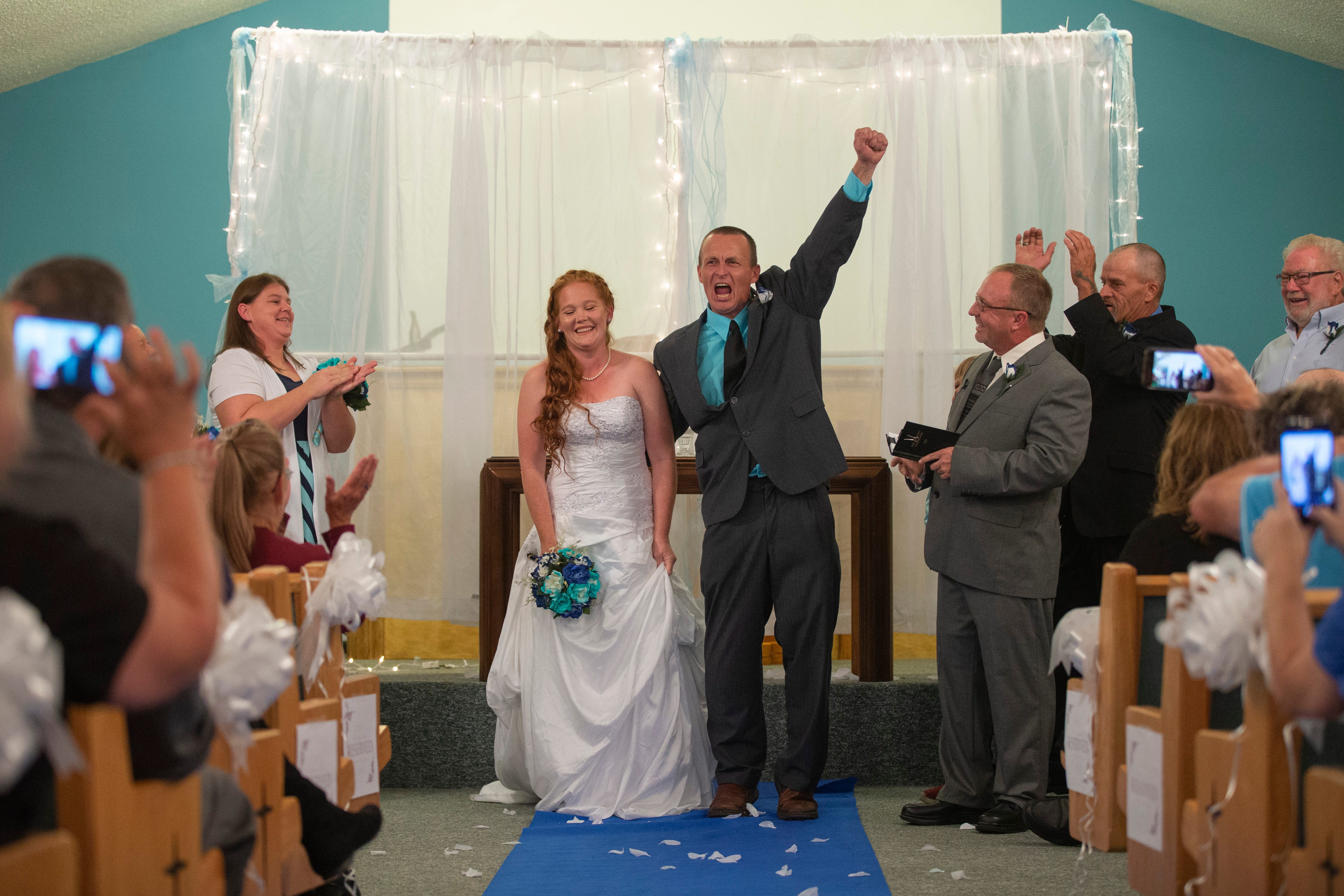 Tiffanie and Jacob Howell react after wrapping up their wedding ceremony at the New Covenant Church in Austin, Indiana. Sept. 22, 2018