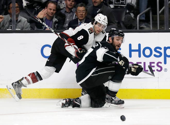 Arizona Coyotes' Nick Schmaltz, top, passes as Los Angeles Kings' Alec Martinez defends during the third period of an NHL hockey game Tuesday, Dec. 4, 2018, in Los Angeles.