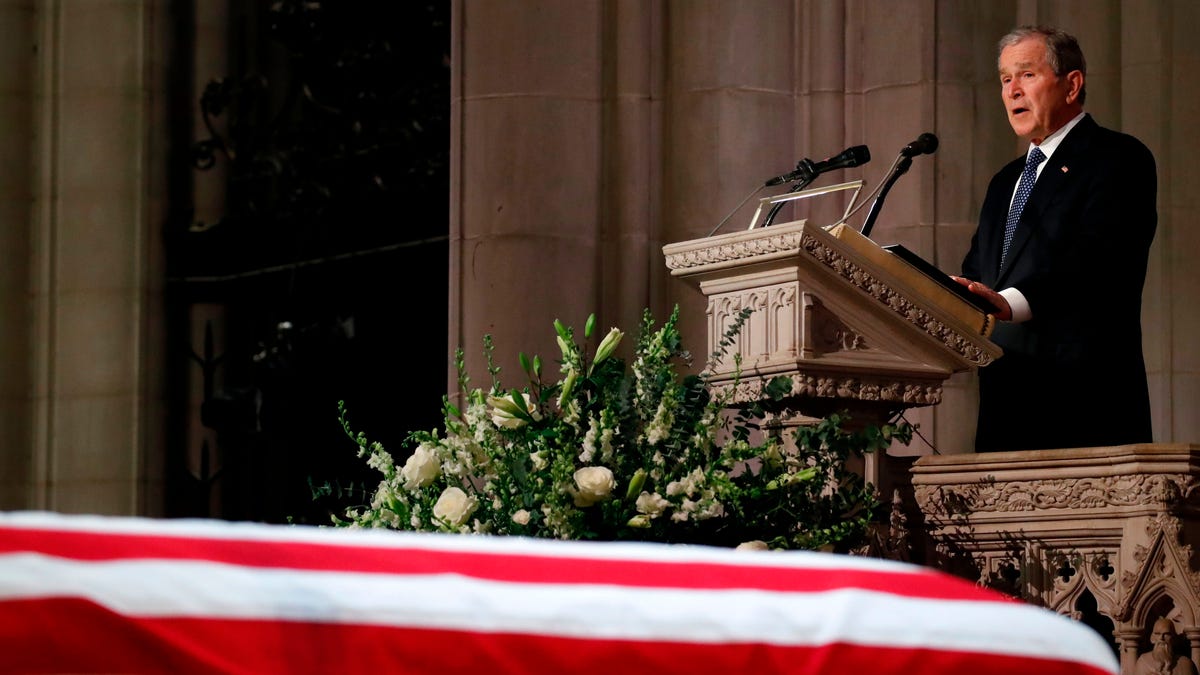 Former President George W. Bush speaks next to the flag-draped casket of his father, during the State Funeral for former President George H.W. Bush at the National Cathedral on December 5, 2018, in Washington,DC.