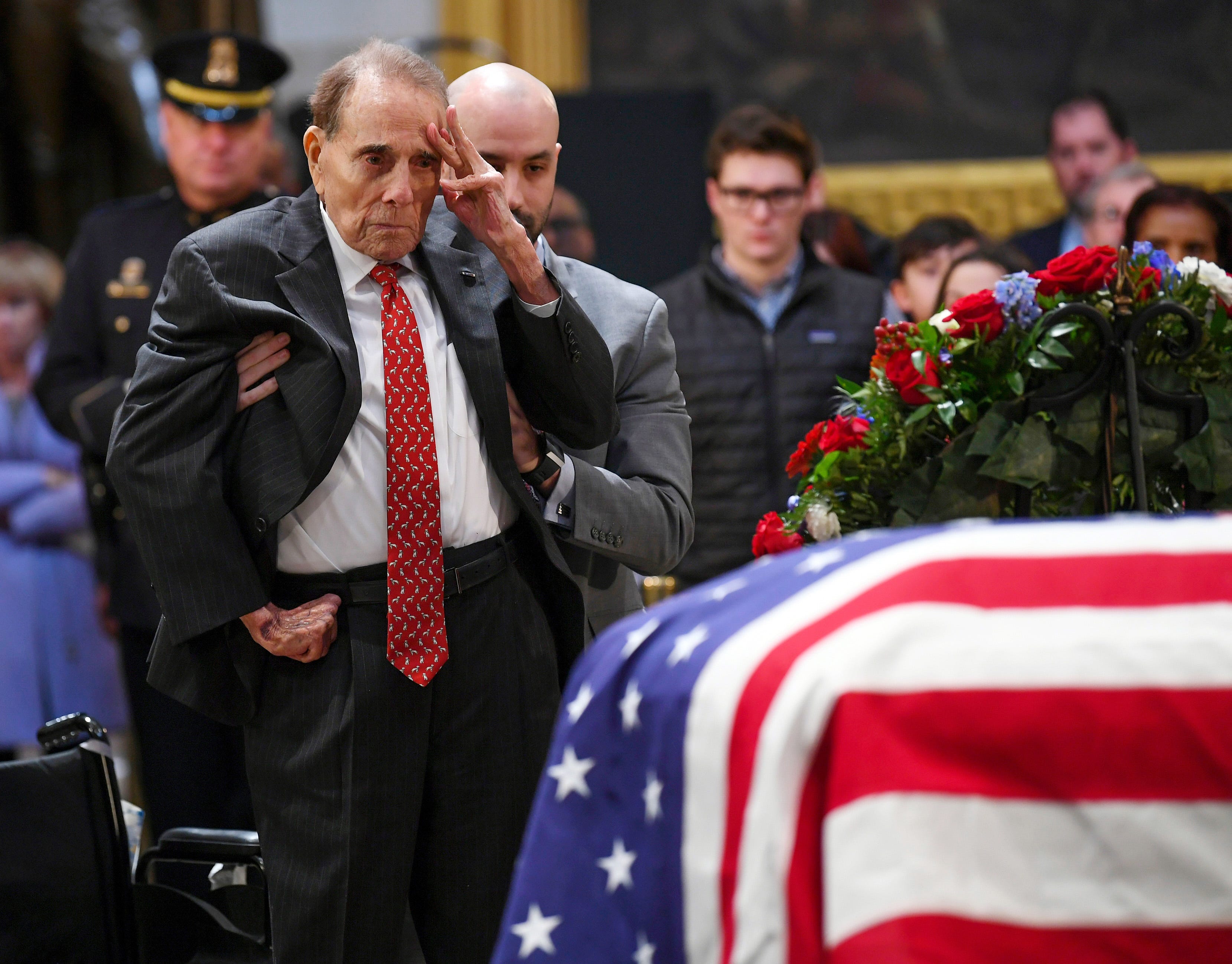 Bob Dole saluted a fellow World War II veteran under the Capitol dome as he rose to honor George H.W. Bush, Dec. 4, 2018. 
Dole, the 95-year-old former Senate majority leader, relied on an aide to help him stand on the floor of the Capitol rotunda before offering his gesture beside the casket of Bush, his onetime rival in the 1988 Republican presidential primary. Bush's spokesman, Jim McGrath, described the salute as "a last, powerful gesture of respect from one member of the Greatest Generation, @SenatorDole, to another."Dole was among mourners filing into the rotunda to pay respects to Bush on day two of his lying in state, a day that also drew Colin Powell, his former Joint Chiefs of Staff chairman, and Sully, the yellow Labrador who worked as the former president's service dog.