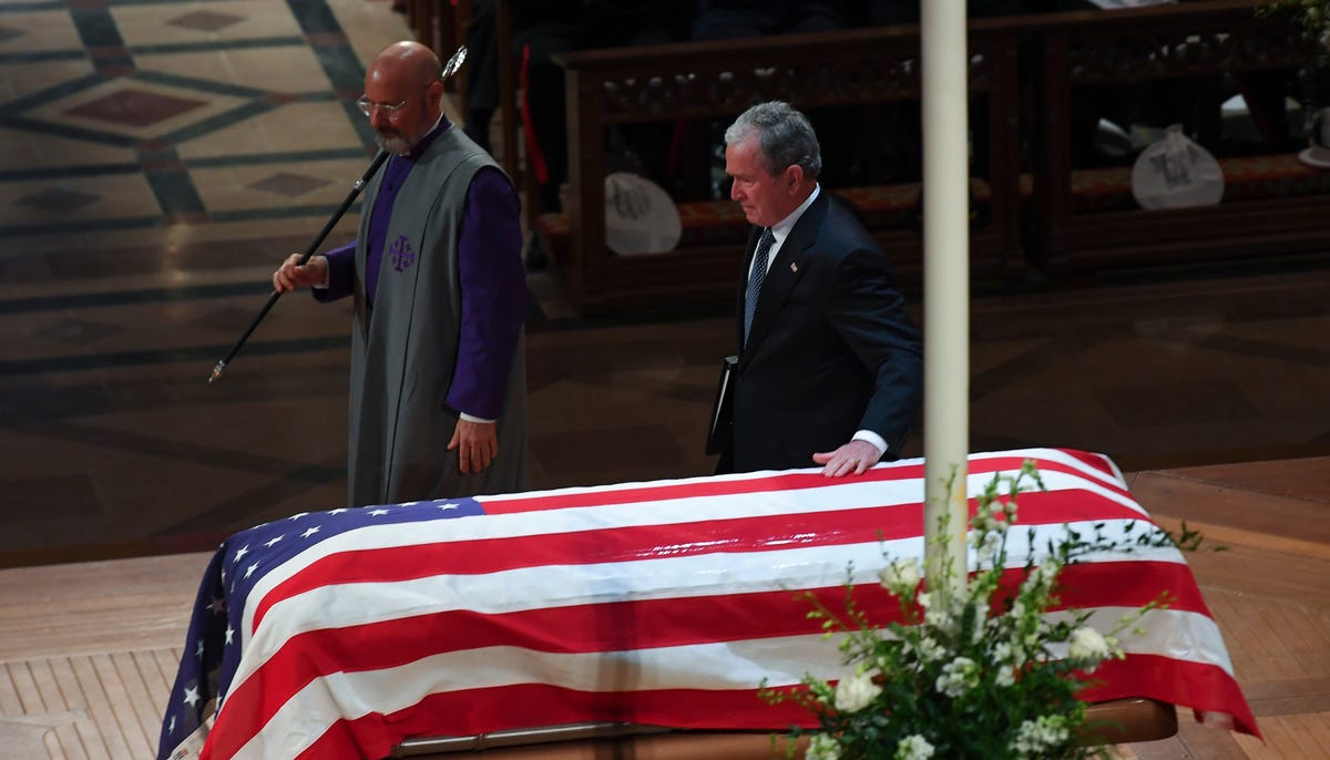 Former President George W. Bush touches his father's casket after speaking about him during the former president's state funeral at the Washington National Cathedral.