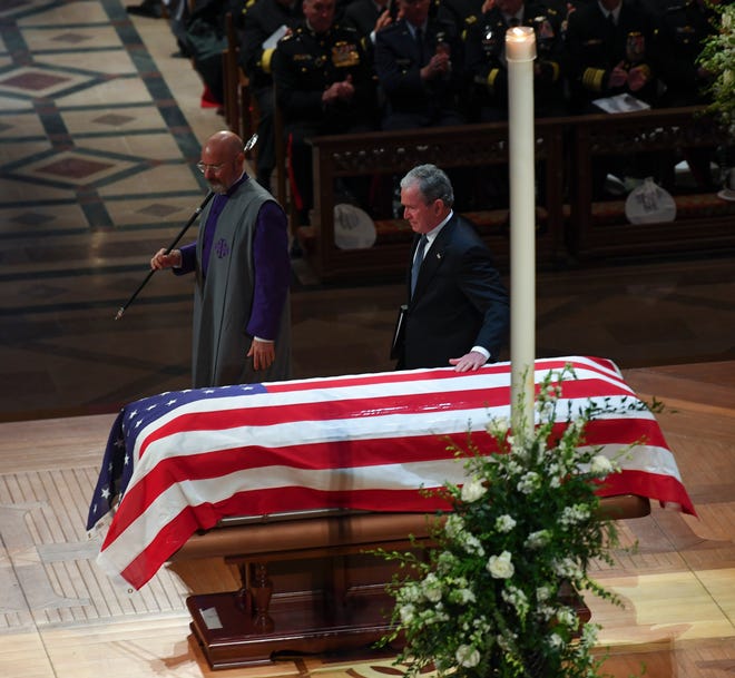 Former President George W. Bush touches his father's casket after speaking about him during the former president's state funeral at the Washington National Cathedral.
