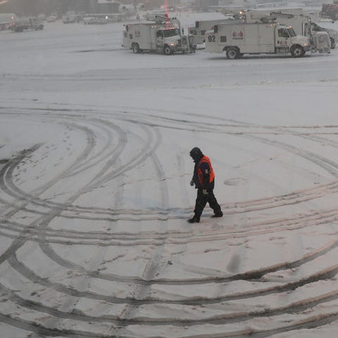 A ground crew member walks through the snow at...