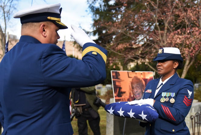 In this Dec. 5, 2018 photo, Rear Adm. Andrew Tiongson, commander First Coast Guard District, salutes Petty Officer 1st Class Tija Hopkins as she hands over a folded American flag during funeral services for Olivia Hooker in White Plains, N.Y. Hooker, the first African-American woman to serve in the U.S. Coast Guard and one of the last survivors of a race riot in Oklahoma, has been laid to rest with military honors. Hooker passed away on Nov. 21, 2018, at the age of 103.  (Petty Officer 3rd Class Steve Strohmaier/U.S. Coast Guard via AP)