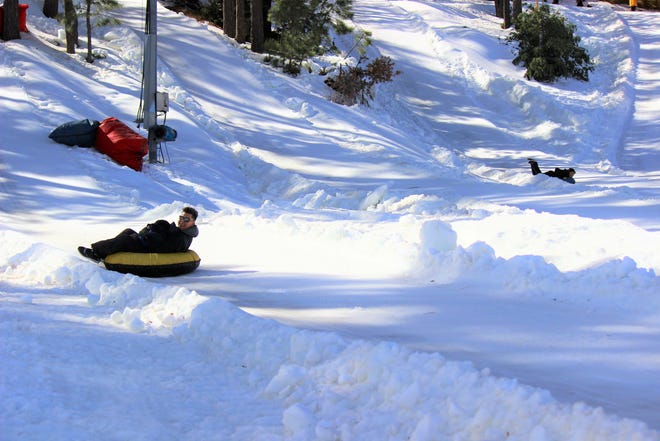 Even adults have fun snow tubing. The man is having a blast as he zooms down the hill on a snow tube.