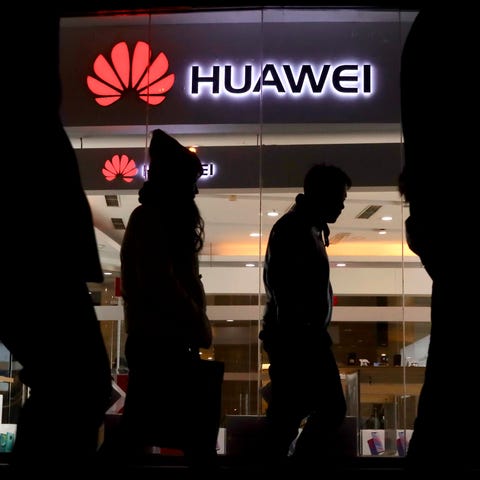 Pedestrians walk past a Huawei retail shop in...