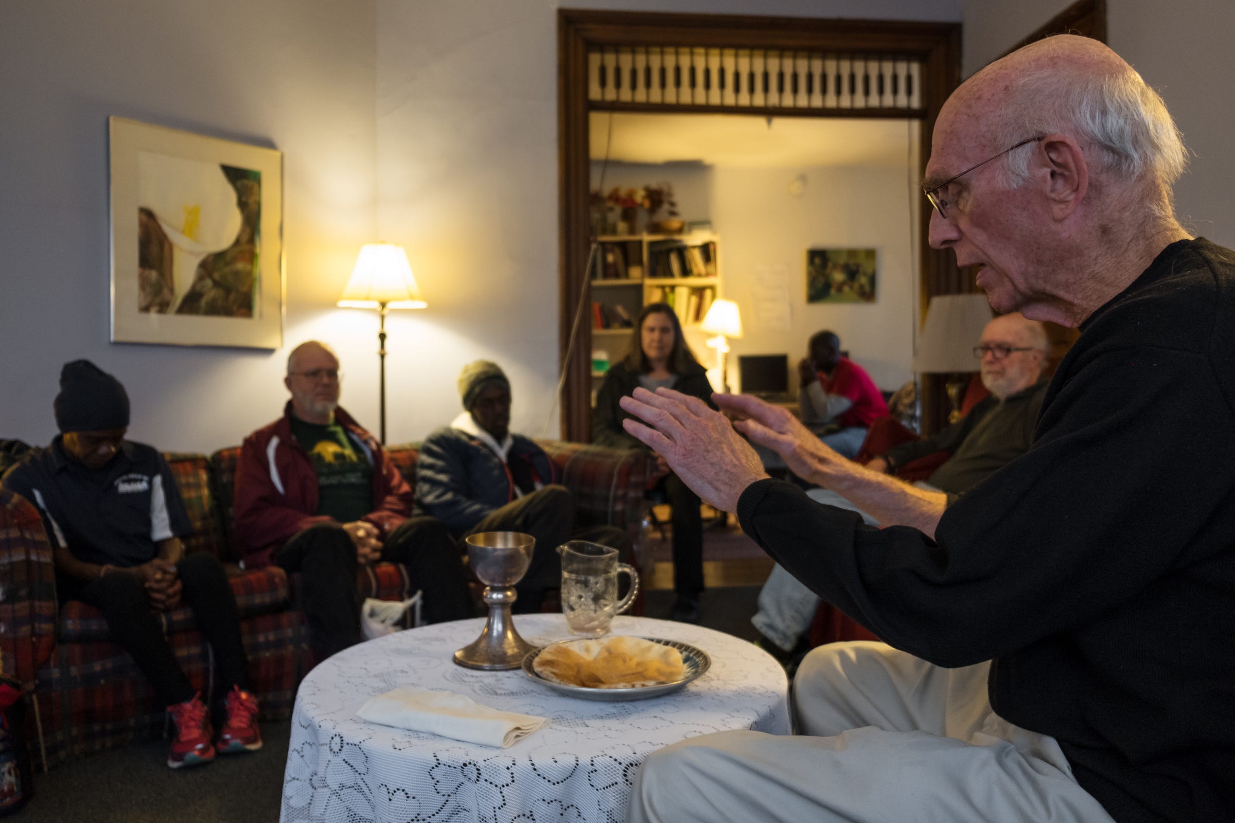 Father Tom Lumpkin raises his hands in prayer before the Eucharist, in this case a slab of pita bread, during an informal Mass at The Day House, a shelter for homeless women in North Corktown, on Sunday, Sept. 9, 2018. 