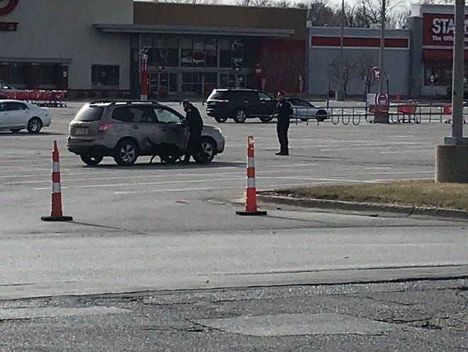 A police K9 officer searches near a vehicle in the parking lot of Target in Altoona.
