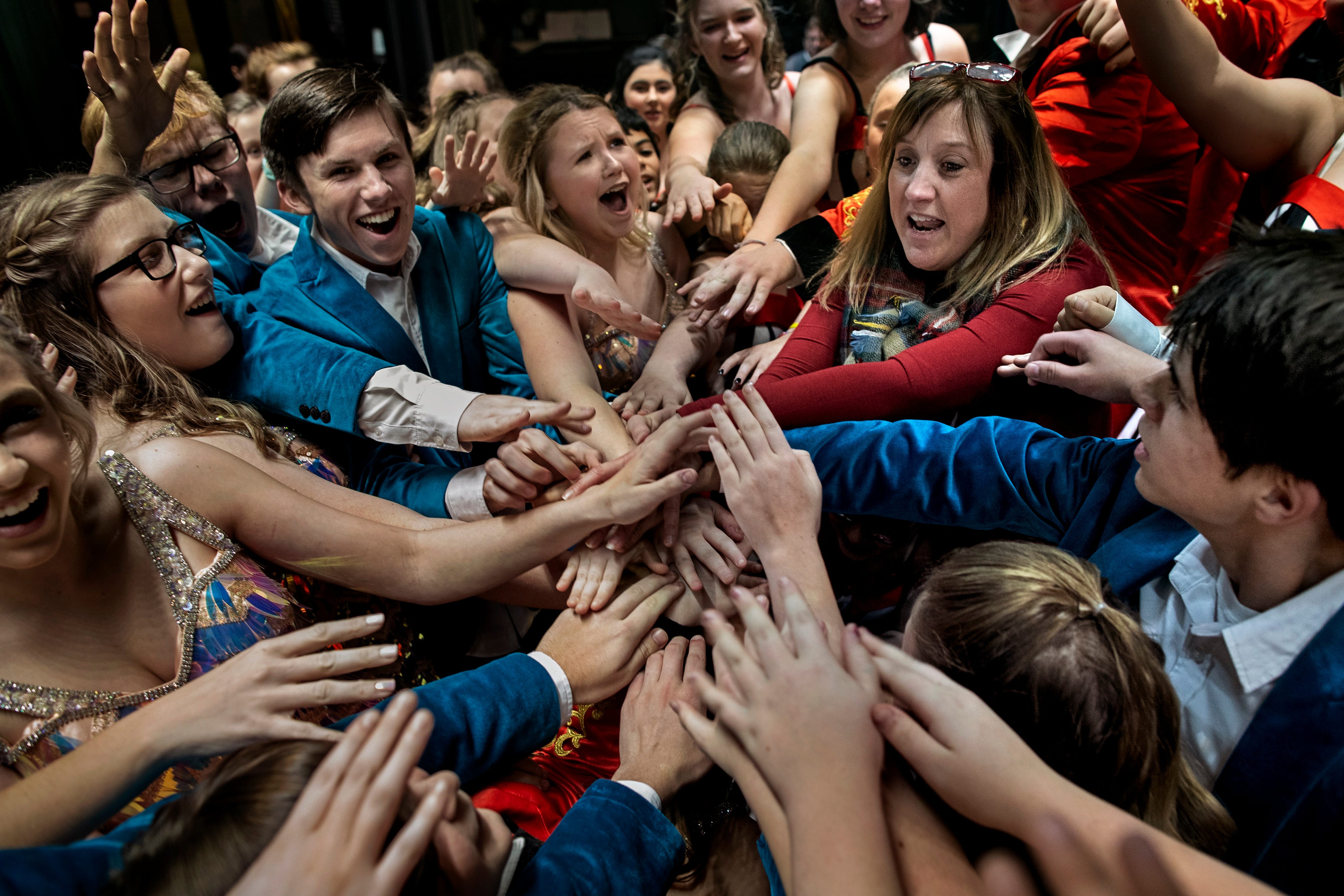 Kathy Risk-Sego, right, reaches her hands in to a sea of hands made up of her high school and middle school show choir performers for a team chant before their first performance of the year. "I'm super proud. For some it was their fist performance ever," Risk-Sego said. "It's really exciting to see it start to come together." Dec. 10, 2018