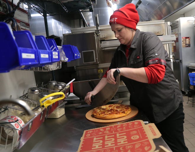 Krislyn Yoxthemier cuts up a pizza at the new Pizza Hut on Lexington Avenue in Mansfield.