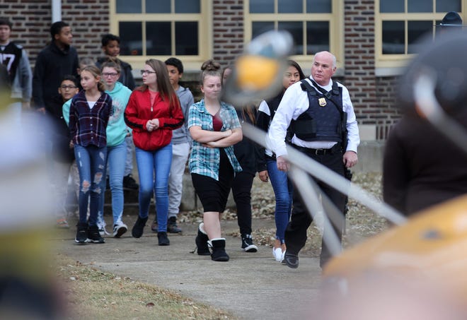 Police escort children onto buses as Dennis Intermediate School is evacuated Thursday following an active shooter on the campus. The only fatality at the school was the shooter who reportedly took his own life.