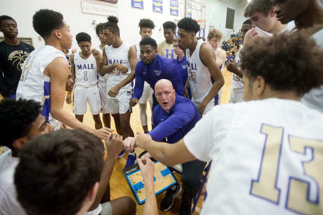 Male head basketball coach Timothy D. Haworth joins hands with his team toward the end of a time-out.14December 2018