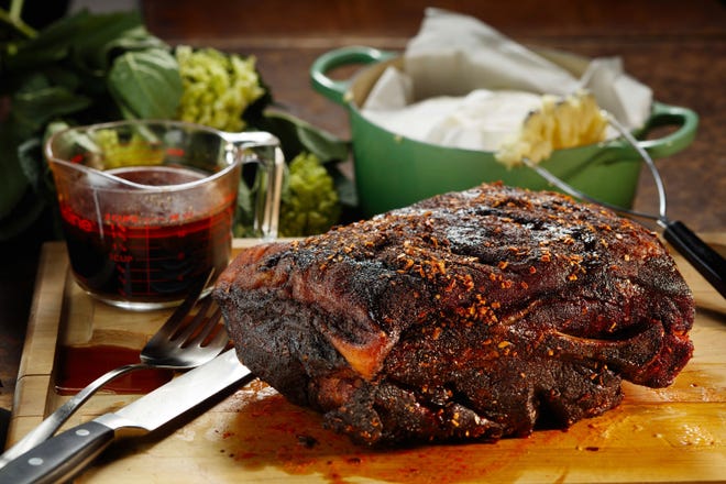 The pork shoulder slow-roasts to a mahogany finish, picking up color and lots of flavor from a chile rub. The mashed potatoes, background, stay hot covered with parchment paper and the lid. (Chris Walker/Chicago Tribune/TNS) 