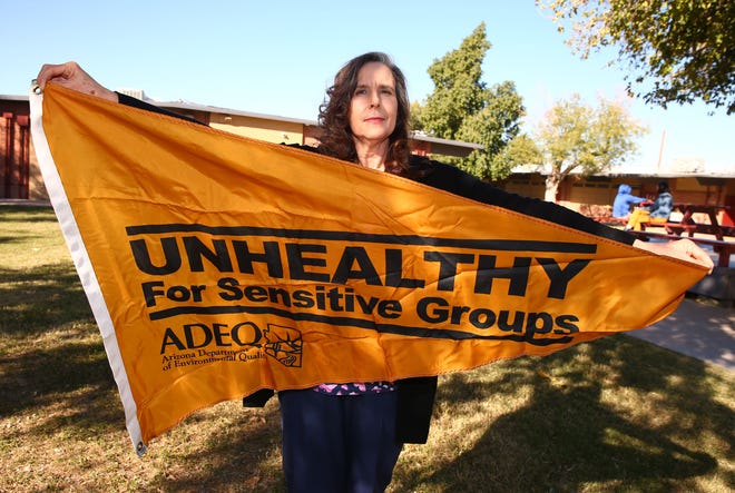 Irene Lopez Elementary School nurse Lois Leon holds the orange flag that warns of unhealthy air pollution that could affect people with respiratory problems.