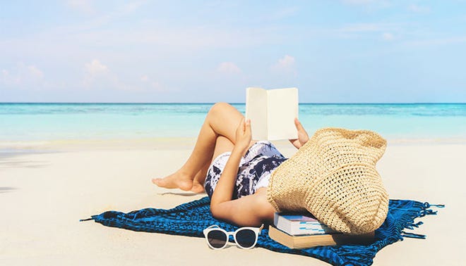 Woman reading a book on the beach in free time summer holiday.