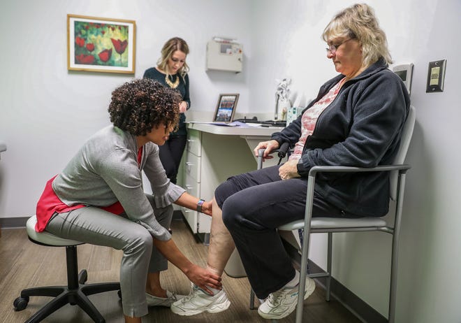 From left, physician assistant Lauren Stokes checks on Paula Watkins' progress since her recent hip replacement at the Midwest Center for Joint Replacement in Indianapolis, Wednesday, Dec. 19, 2018. Watkins and other joint replacement patients across 18 sites have been invited to incorporate an Apple Watch into their rehabilitation regimen for a clinical trial. The watch, paired with mobile app mymobility, guides patients' rehab efforts while tracking their progress through heart rate, daily step counts, recorded exercises and more. 