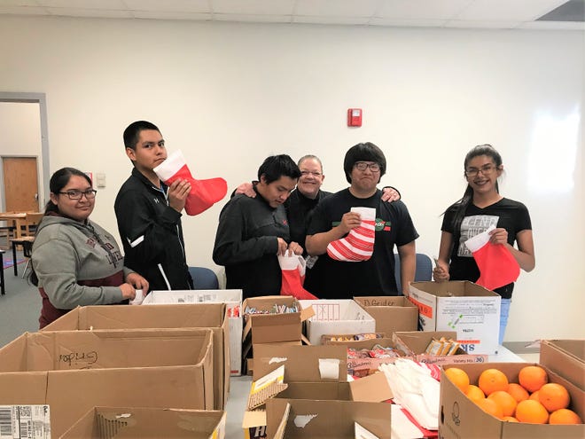Members of the Mescalero Apache School stuffing stockings for younger pupils were from left, Lynell Magoosh,
Varyn Apachito, Jalen Burgess, 
Nico Garcia,  Marshall Comanche
with sponsor Deborah Grider.
