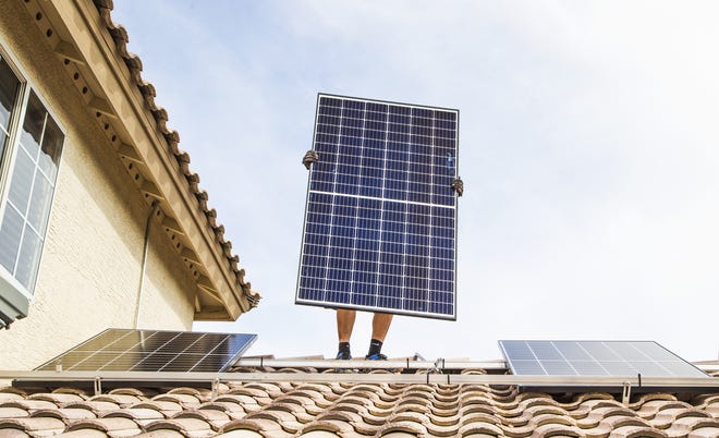 Chris Miller, a solar panel installer for SunHarvest Solar, installs panels on a home in El Mirage on Nov. 20, 2018.
