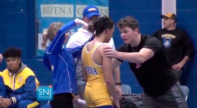 In this image taken from a video provided by SNJTODAY.COM, Buena Regional High School wrestler Andrew Johnson gets his hair cut minutes before his match on Dec. 19.