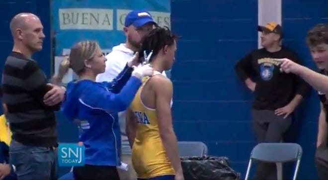In this image taken from a video provided by SNJTODAY.COM, Buena Regional High School wrestler Andrew Johnson gets his hair cut minutes before his match in Buena, N.J., after a referee told Johnson he would forfeit his bout if he didn't have his dreadlocks cut off.