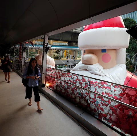 Shoppers walk past a large inflatable Santa Claus...