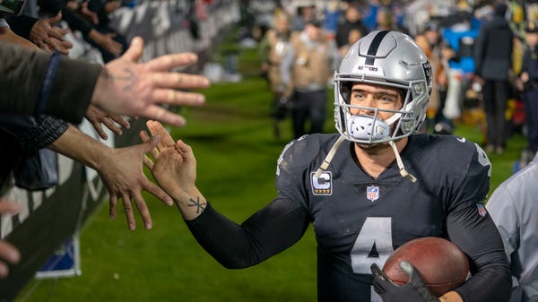 Raiders quarterback Derek Carr high-fives fans...