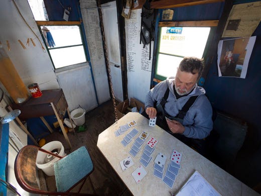 Dan Brokiewicz plays solitaire in his ice fishing shack while monitoring his tip-ups on Dec 24 on Shawano Lake in Cecil Tip-ups are fishing lines placed in an ice hole with a mechanical strike indicator that raises a flag when a fish is on the line