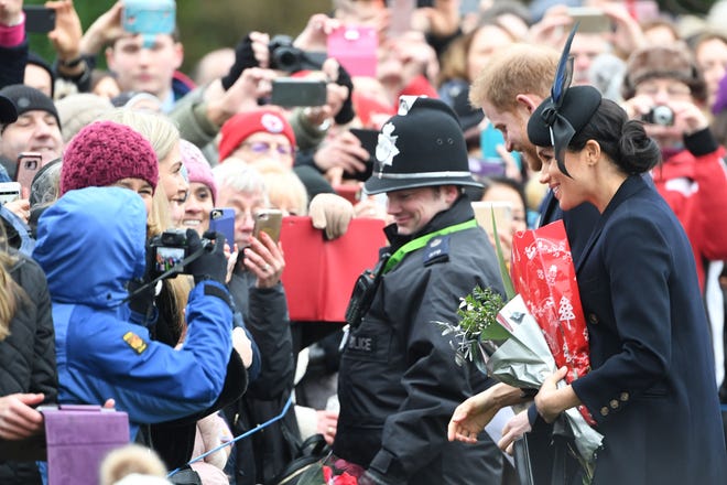 Duches Meghan of Sussex and Prince Harry greet cellphone-wielding fans as they depart after the royal family's annual Christmas Day service at St Mary Magdalene Church in Sandringham, Norfolk, on Dec. 25, 2018.