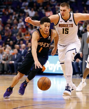 Phoenix Suns guard Devin Booker (1) drives as Denver Nuggets center Nikola Jokic (15) defends during the second half of an NBA basketball game, Saturday, Dec. 29, 2018, in Phoenix.