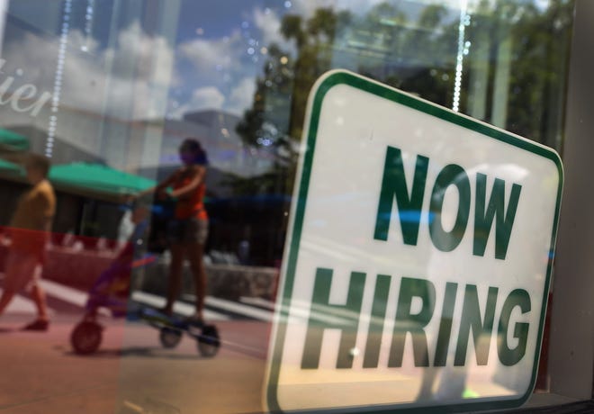 FILE: A ''Now Hiring'' sign is seen in the store front window.