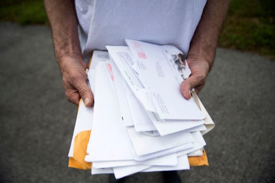 Alan Chrisman holds medical bills and records near the McDonald's where he worked at as a maintenance employee before being diagnosed with stage 4 colorectal cancer. This photo has been altered to blur the address on the envelope.