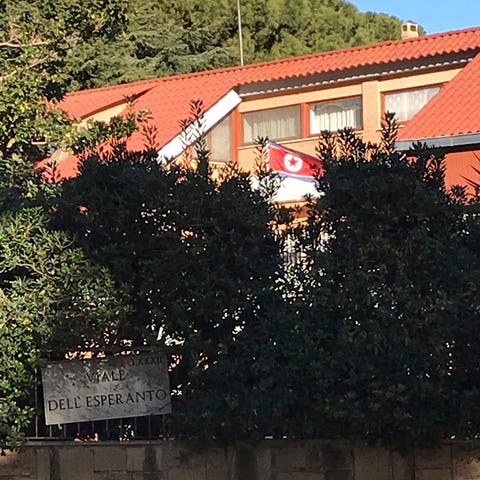 The flag of North Korea waves inside the compound...