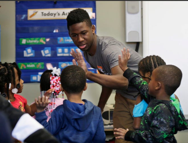 Isouma Shine high-fives students in a preschool class at Next Door Foundation in Milwaukee. Shine is taking part in the Leading Men Fellowship, a program aimed at improving early childhood literacy skills and exposing young men of color to careers in early childhood education.