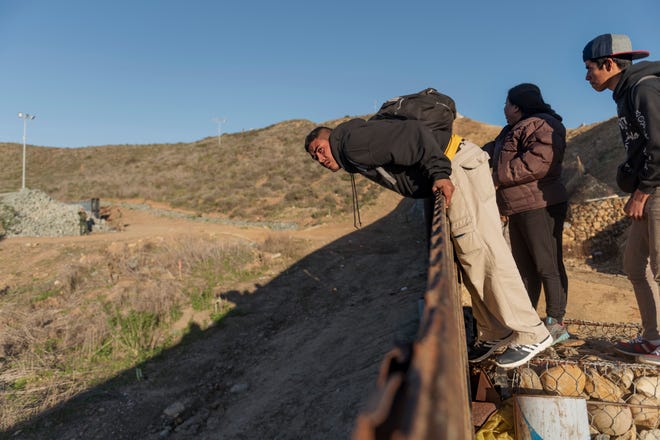 A migrant from Honduras looks from the border fence to the U.S. side before jumping to San Diego from Tijuana, Mexico, on Jan. 3, 2019.